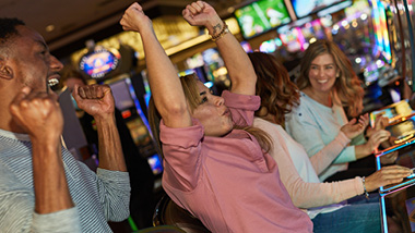 People cheering at a slot machine